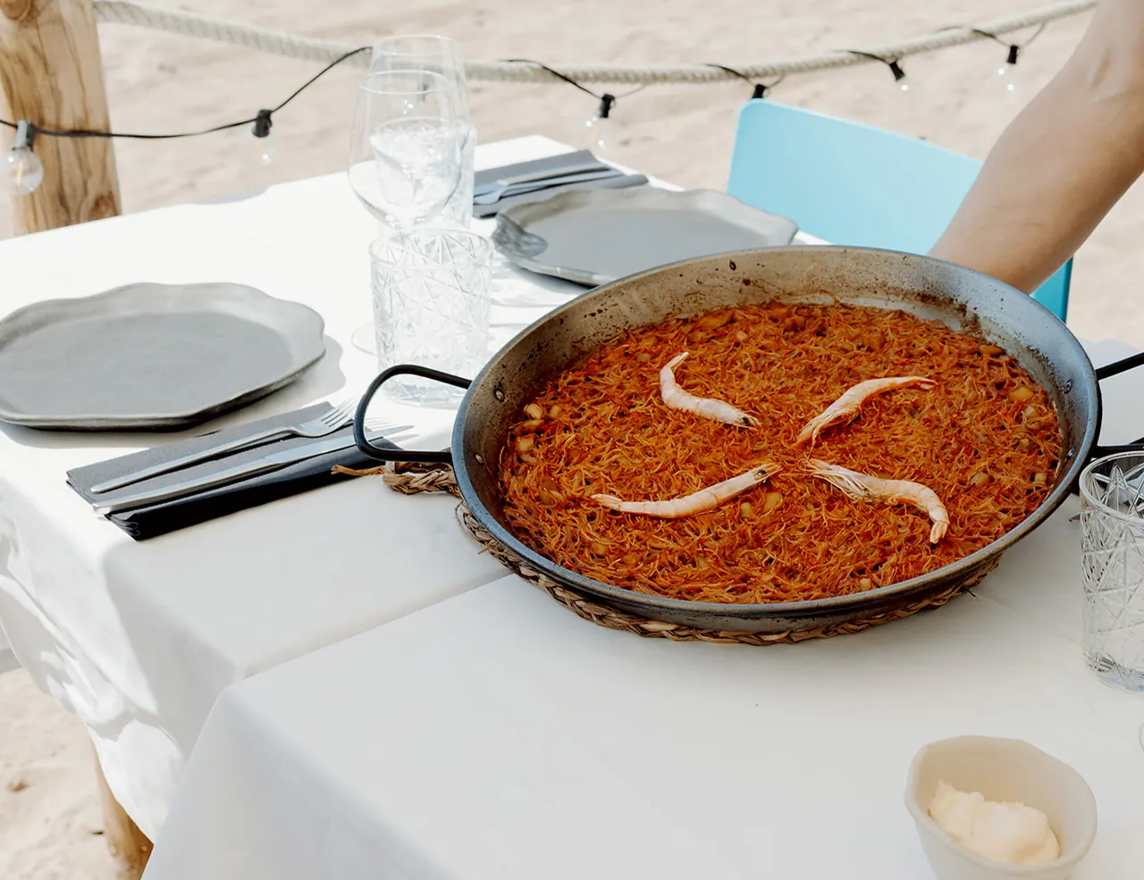 Fideuá aux fruits de mer servie à une table de la paillote de l'Akquaaa, sur le sable de la plage de Calafell